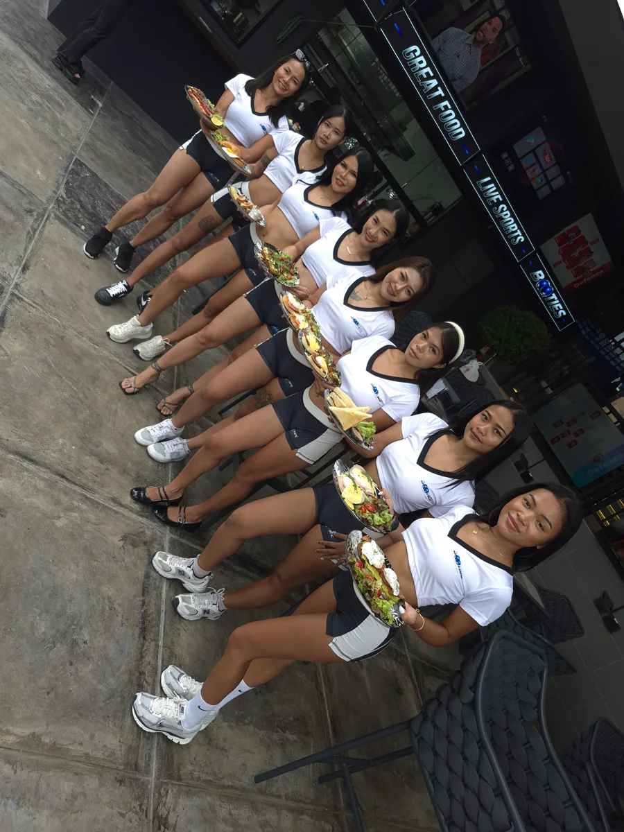 Booties Girls service team outside Booties Sports Bar Pattaya with dishes from the kitchen